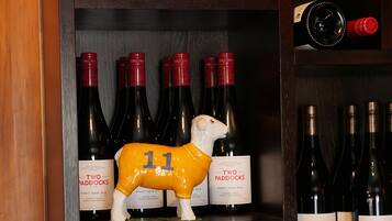 Una botellera con botellas de Two Paddocks Pinot Noir 2013, una figurita de oveja de cerámica blanca y una botella de vino tinto.