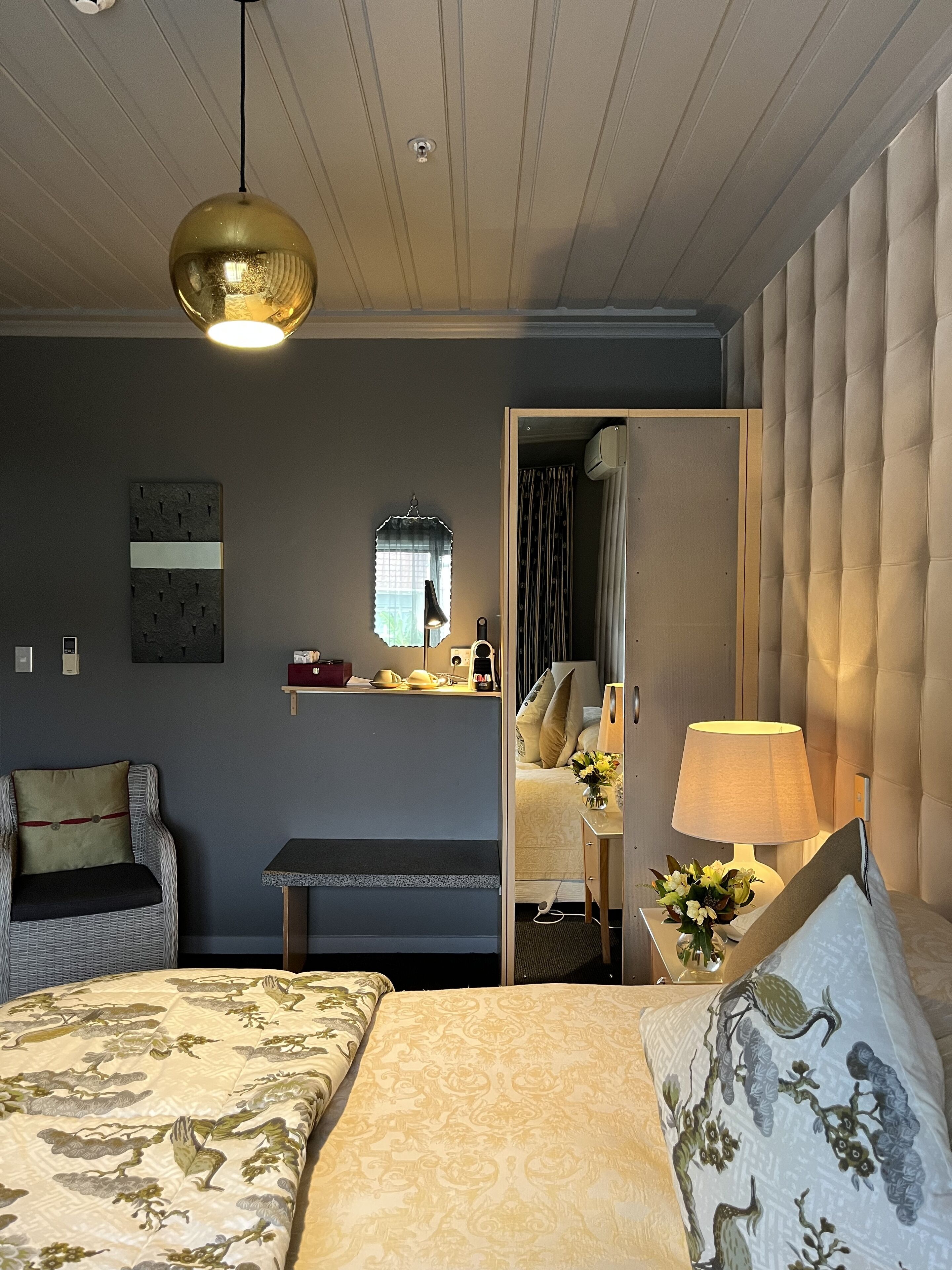 A hotel room with a bed, a chair, a desk, and a mirror.