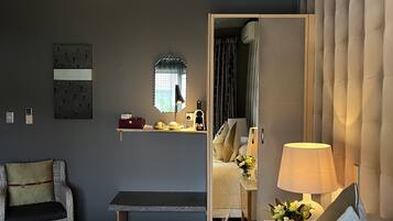 A hotel room with a bed, a chair, a desk, and a mirror.