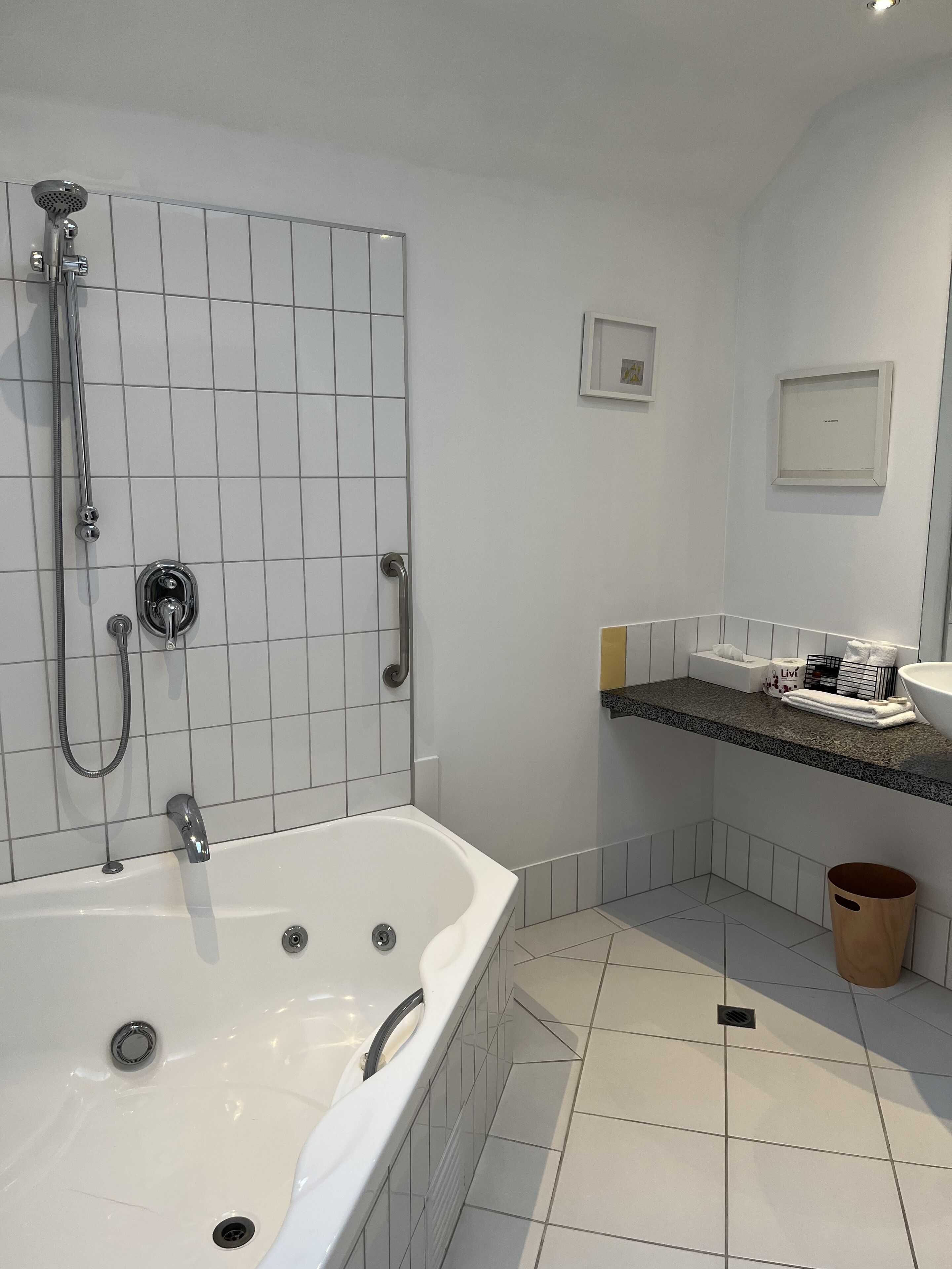 Un bany modern amb una banyera independent, un vàter i un lavabo amb calaix i barra de tovalloles.