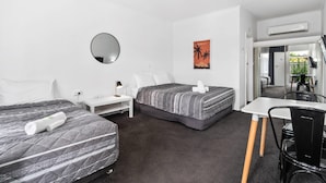 Habitación de hotel con dos camas, un escritorio, una silla, un espejo y un cuadro de Hawái.