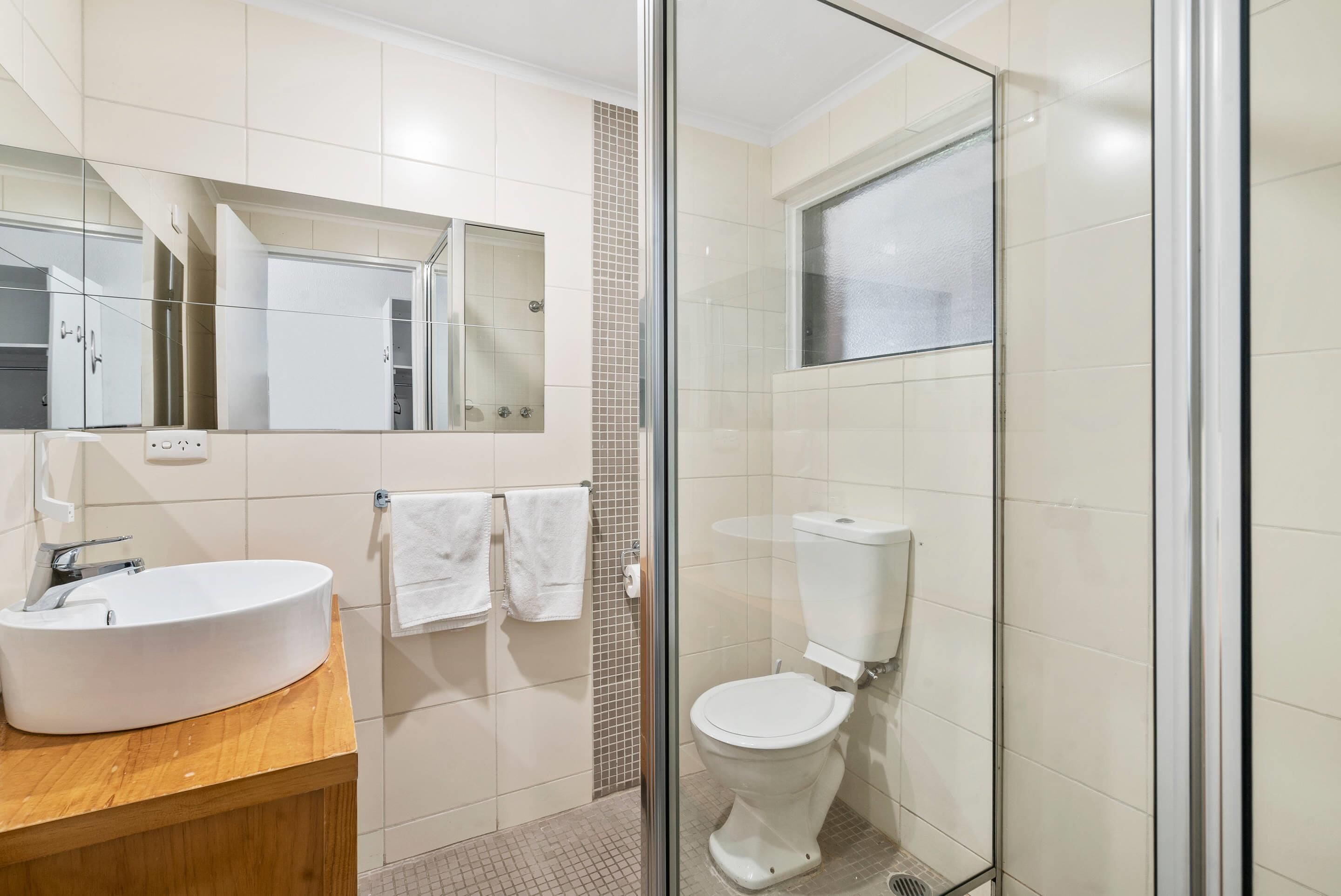 Un baño moderno con cabina de ducha de vidrio, un lavabo blanco y un inodoro.