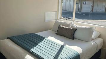 A hotel room with a bed, a window, and a view of the street.