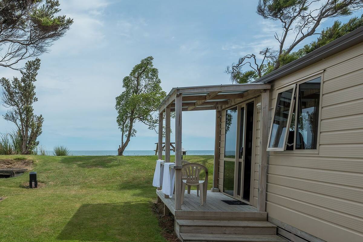 A single-story house with a covered porch, a view of the sea, and a grassy yard.