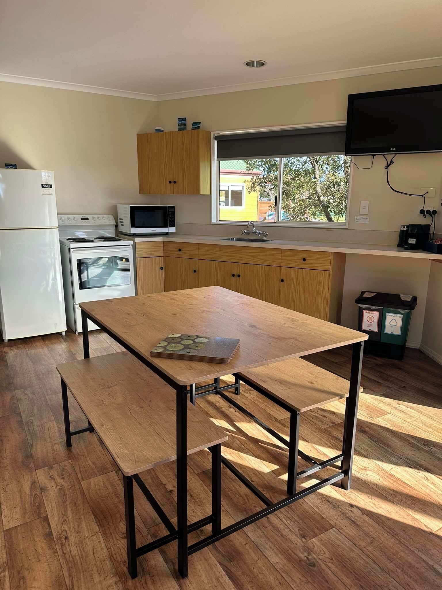 A compact kitchen with a wooden table, a refrigerator, a microwave, and a stove.