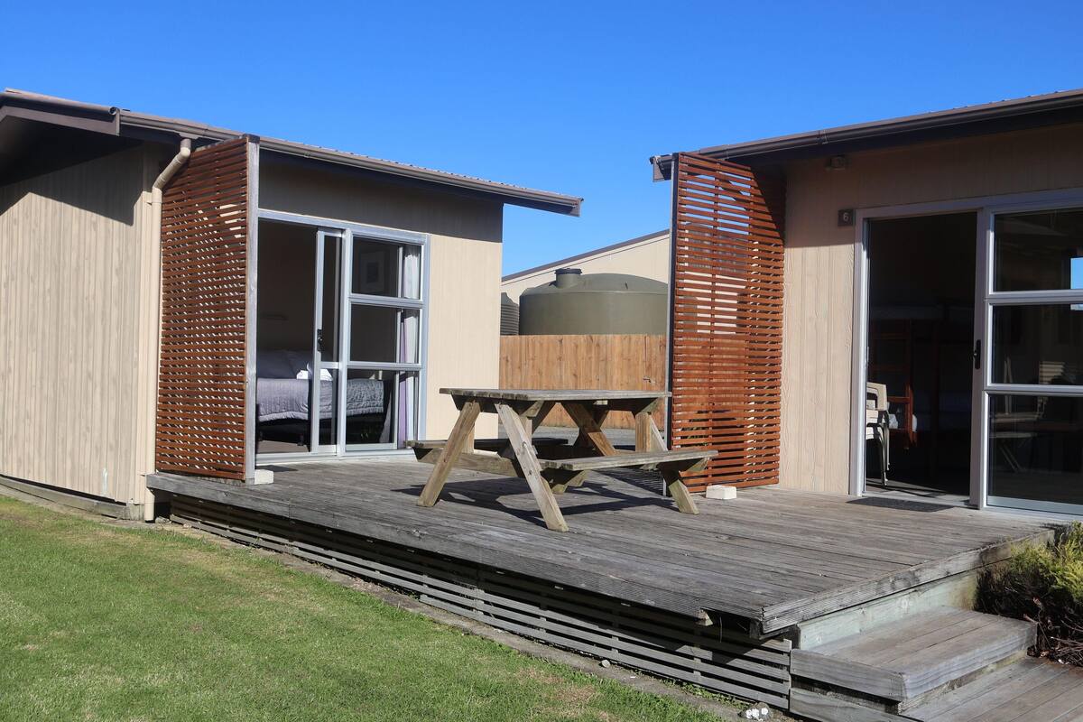A modern house with a wooden deck, a large water tank, and a sliding glass door.