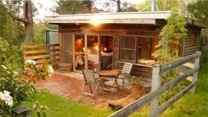 Een rustieke chalet met een patio, een houten terras en een kleine zithoek buiten.