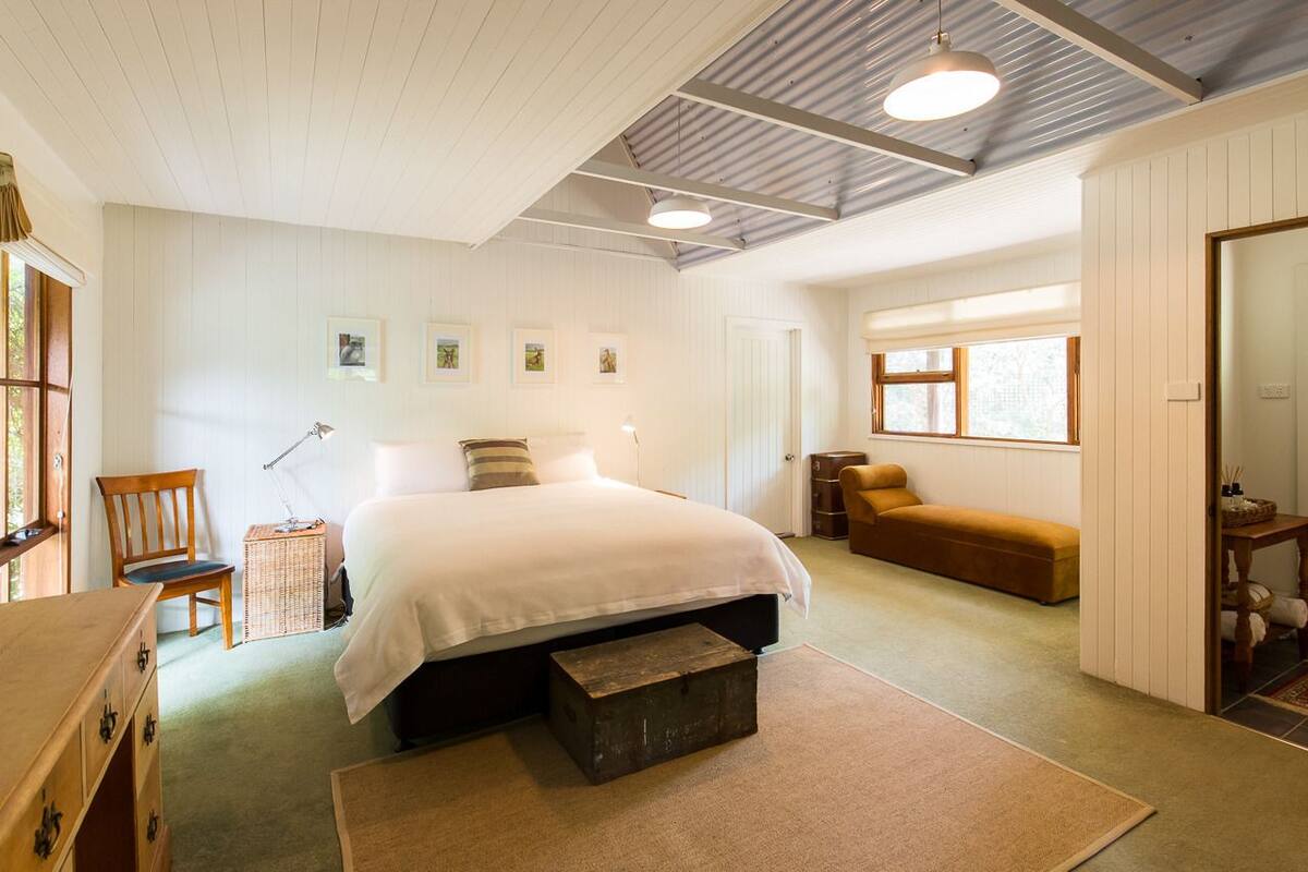 Een slaapkamer met een bed, een stoel, een klein tafeltje en een bank.