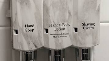 Dispensadores de jabón de manos, loción corporal y crema de afeitar en un baño.