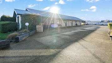 A building with a sloped roof, a parking lot, and a clear sky.