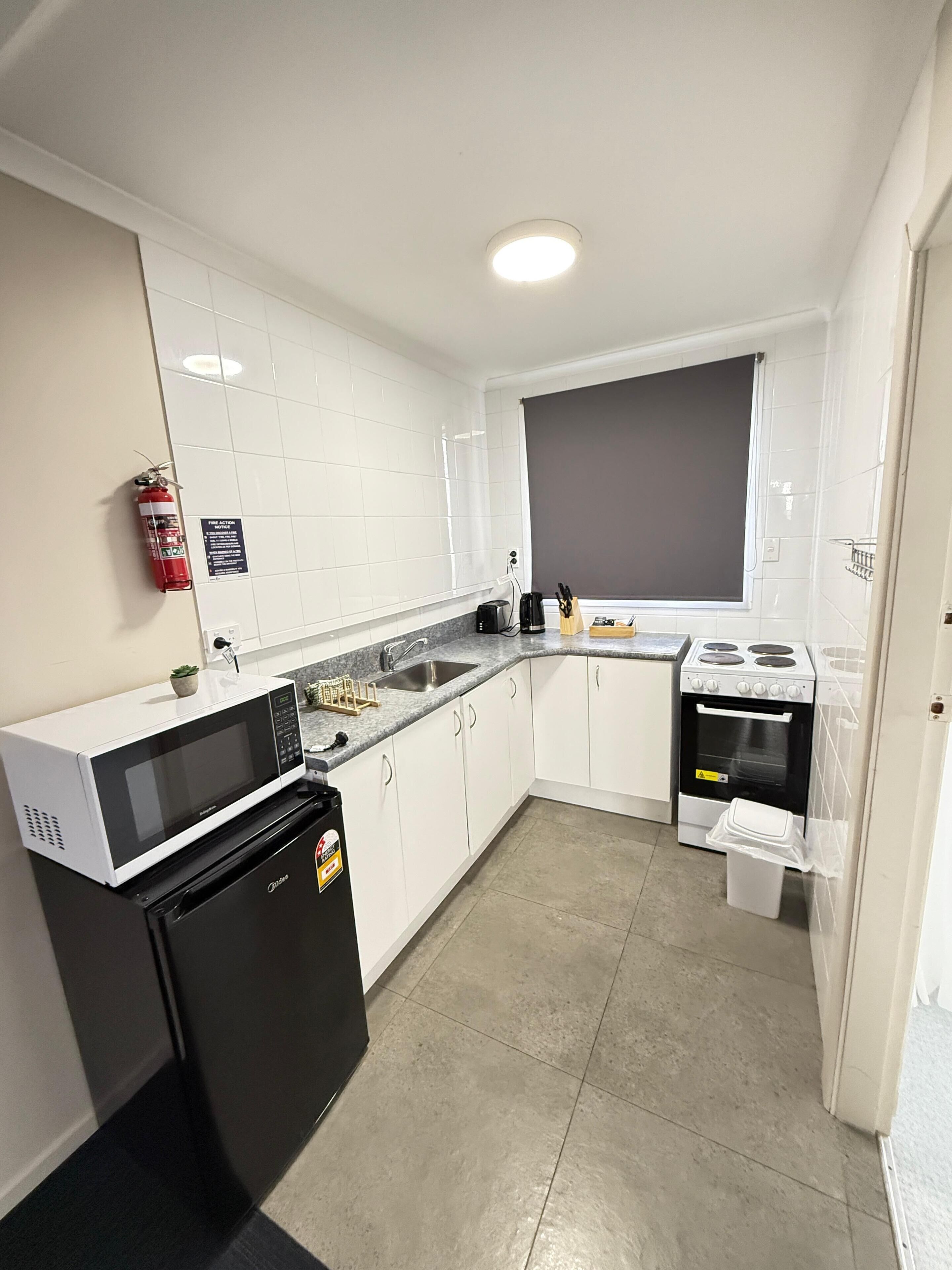 A modern kitchen with white cabinets, a black refrigerator, a stove, and a sink.