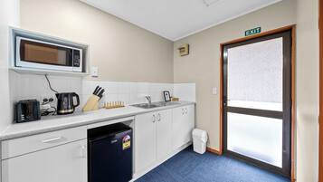 A compact kitchen with a microwave, toaster, coffee maker, sink, and cabinets.