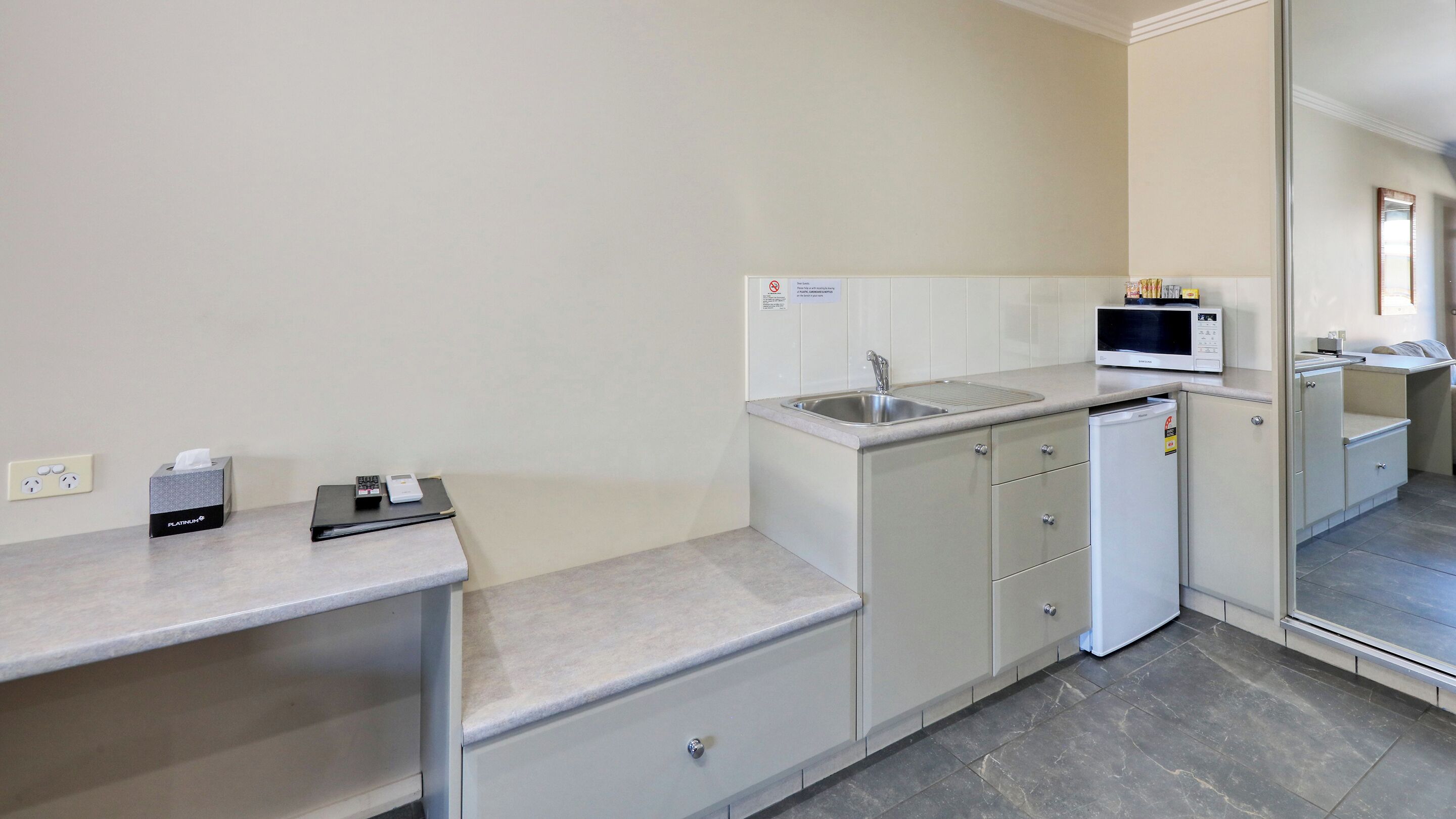 Una kitchenette compacta con un lavamanos, microondas y refrigerador pequeño.