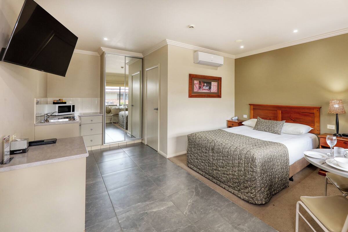 A hotel room with a bed, bedside table, and a small dining area.