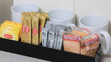 Exhibición de café y galletas con té Lipton, café Moccona, paquetes de azúcar blanco y galletas Arnott's.