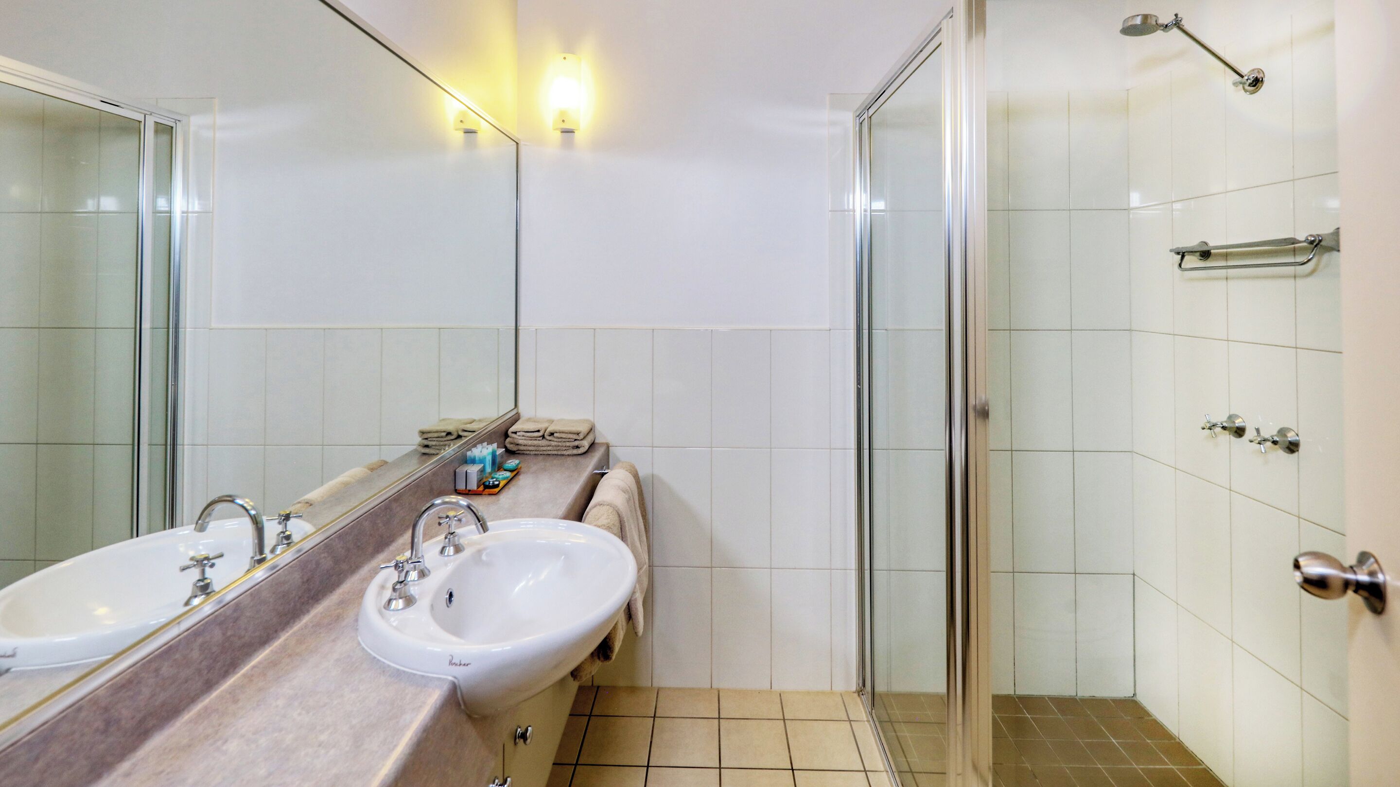 A modern bathroom with two sinks, a glass shower enclosure, and a mirror.