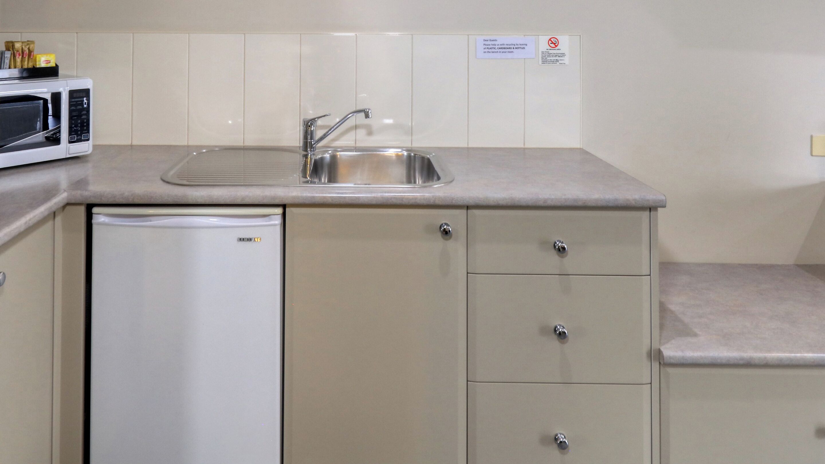 A compact kitchenette with a built-in microwave, a stainless steel sink, and a small refrigerator.