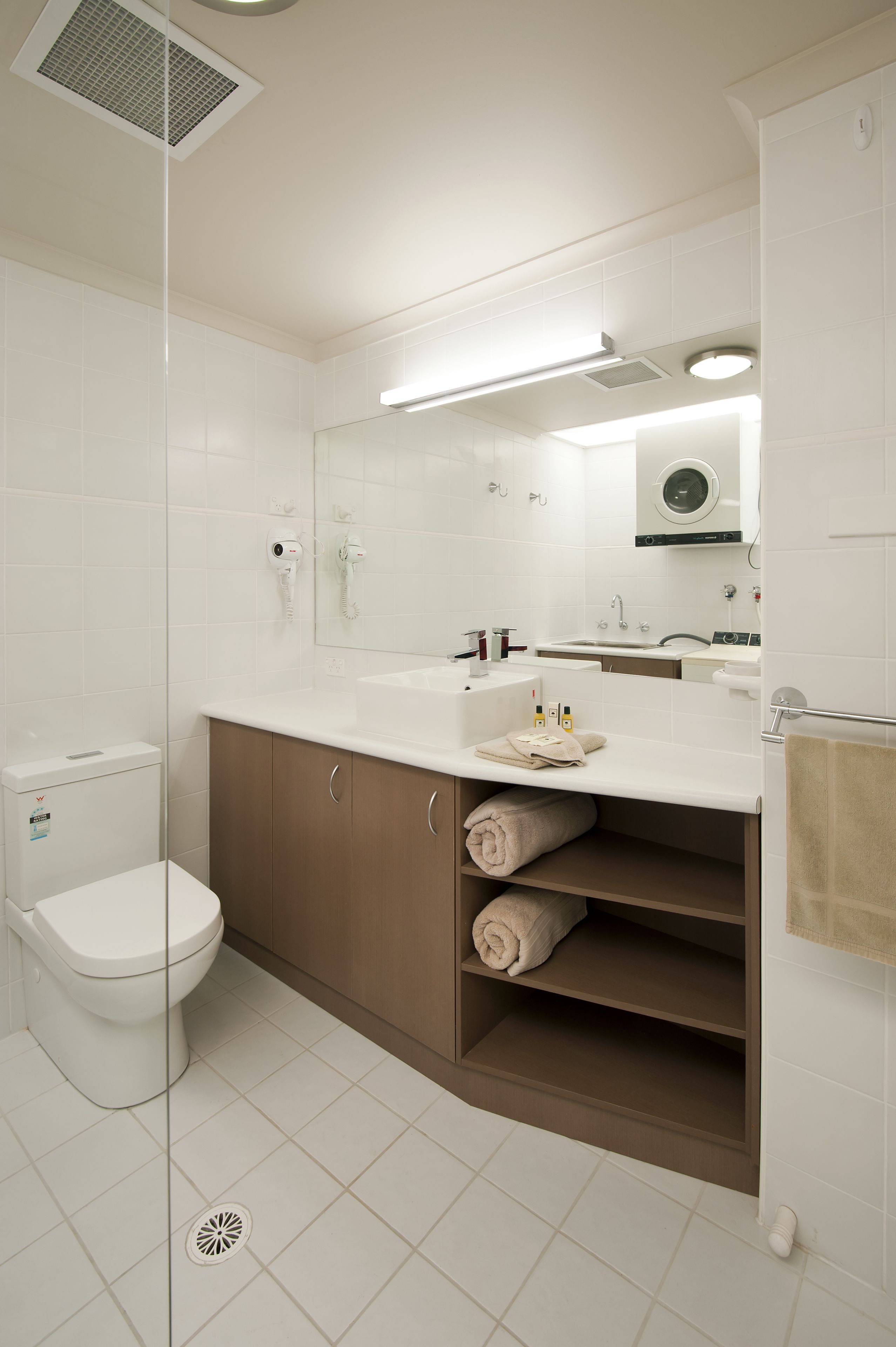 Un baño moderno con inodoro, lavamanos, espejo y espacio para toallas.