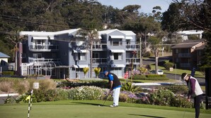 A golf course with a building in the background. - Mollymook Cove Apartments (Mollymook)