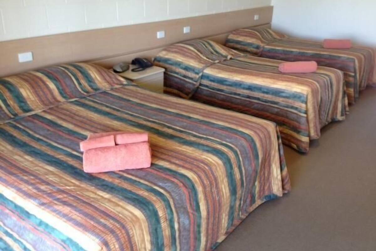 A row of beds with striped bedding and a headboard.