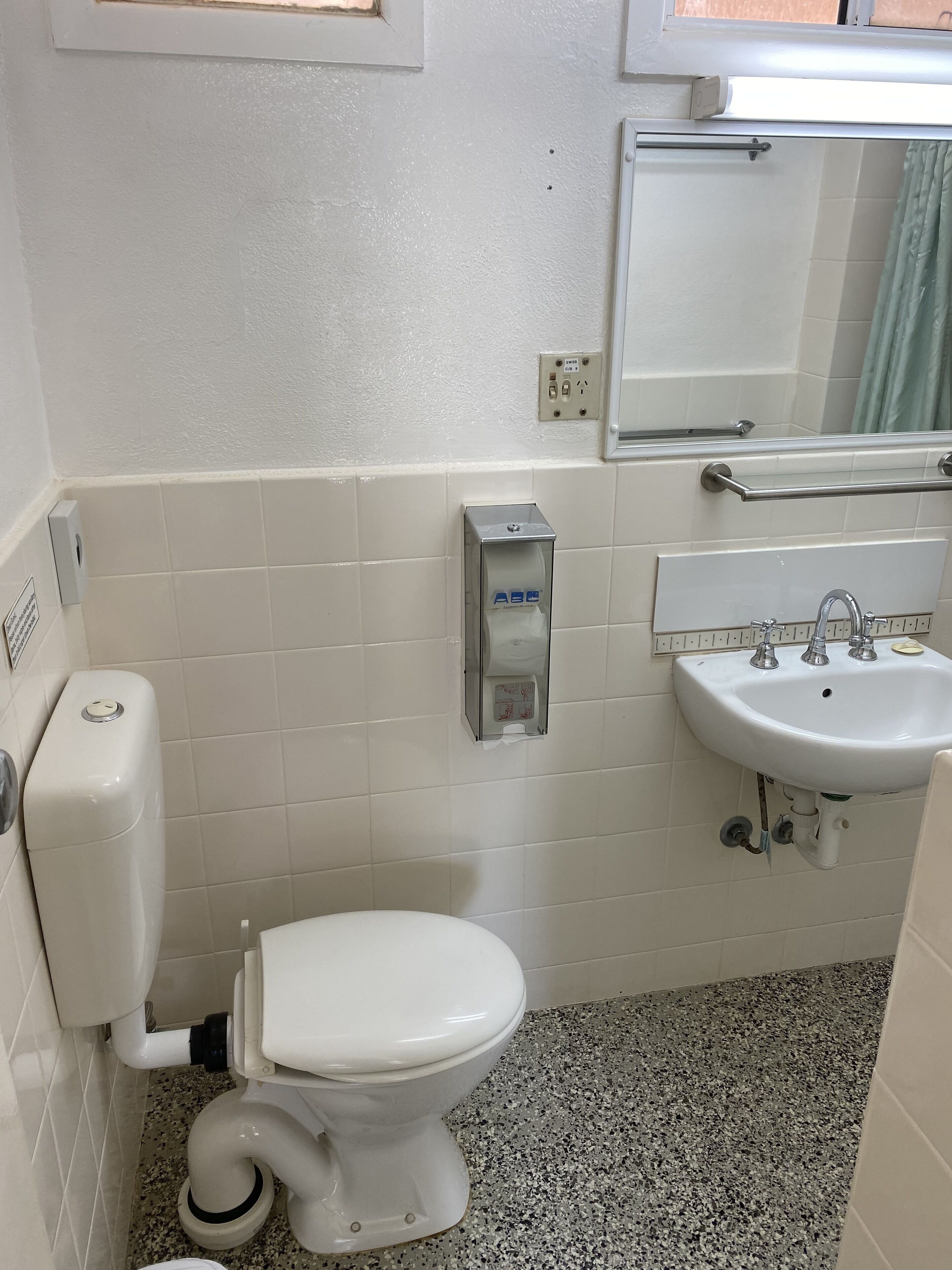 Un baño pequeño con inodoro, lavamanos y espejo.