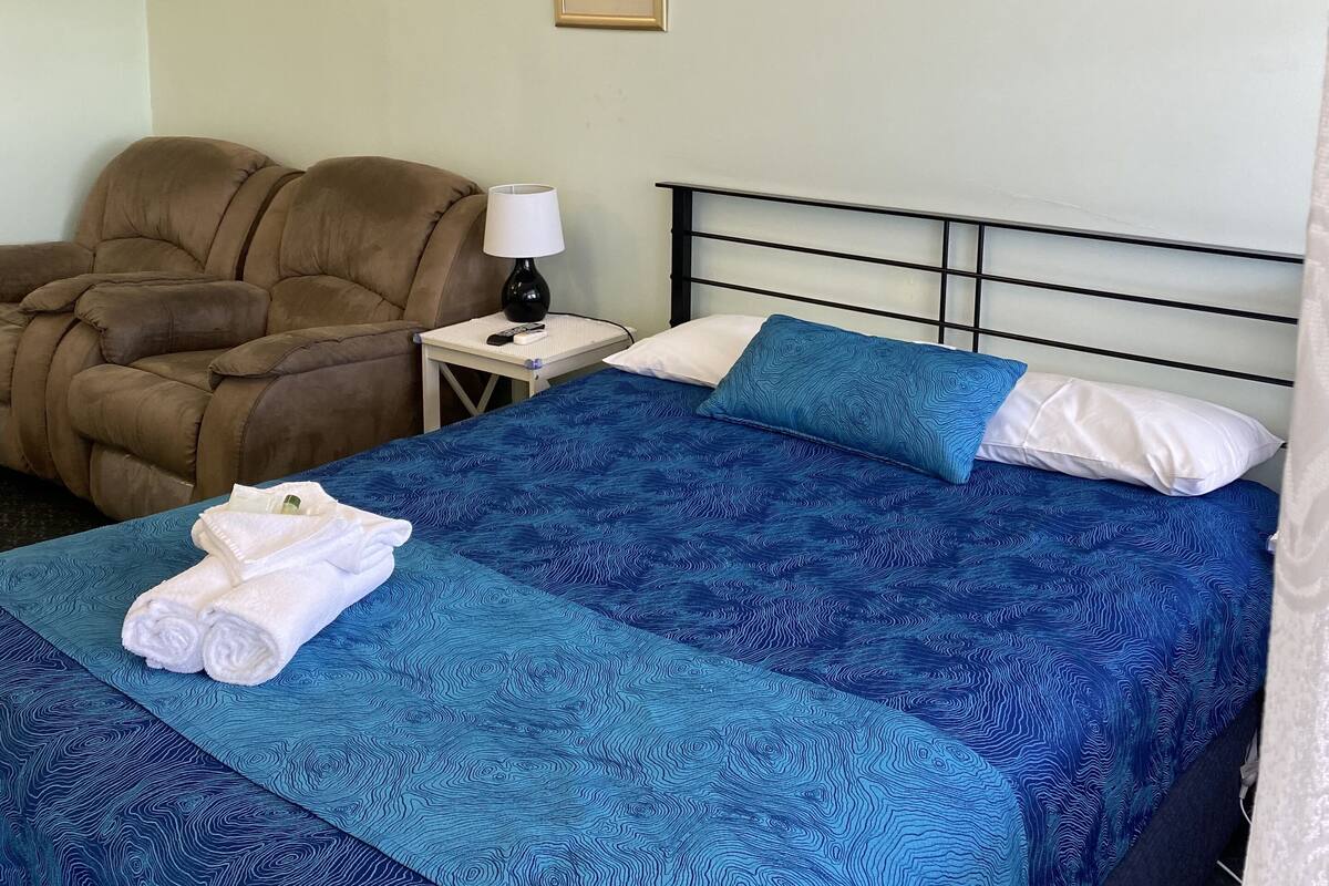 Une chambre d’hôtel avec un lit, un fauteuil de massage et deux tableaux encadrés au mur.