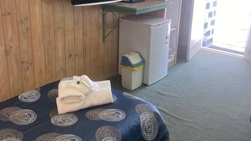 Une chambre d’hôtel équipée d’un lit, d’une télévision, d’un petit réfrigérateur et d’une poubelle.