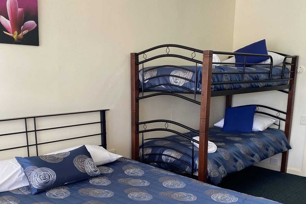 Une chambre avec un lit superposé, un lit simple et un tableau accroché au mur.