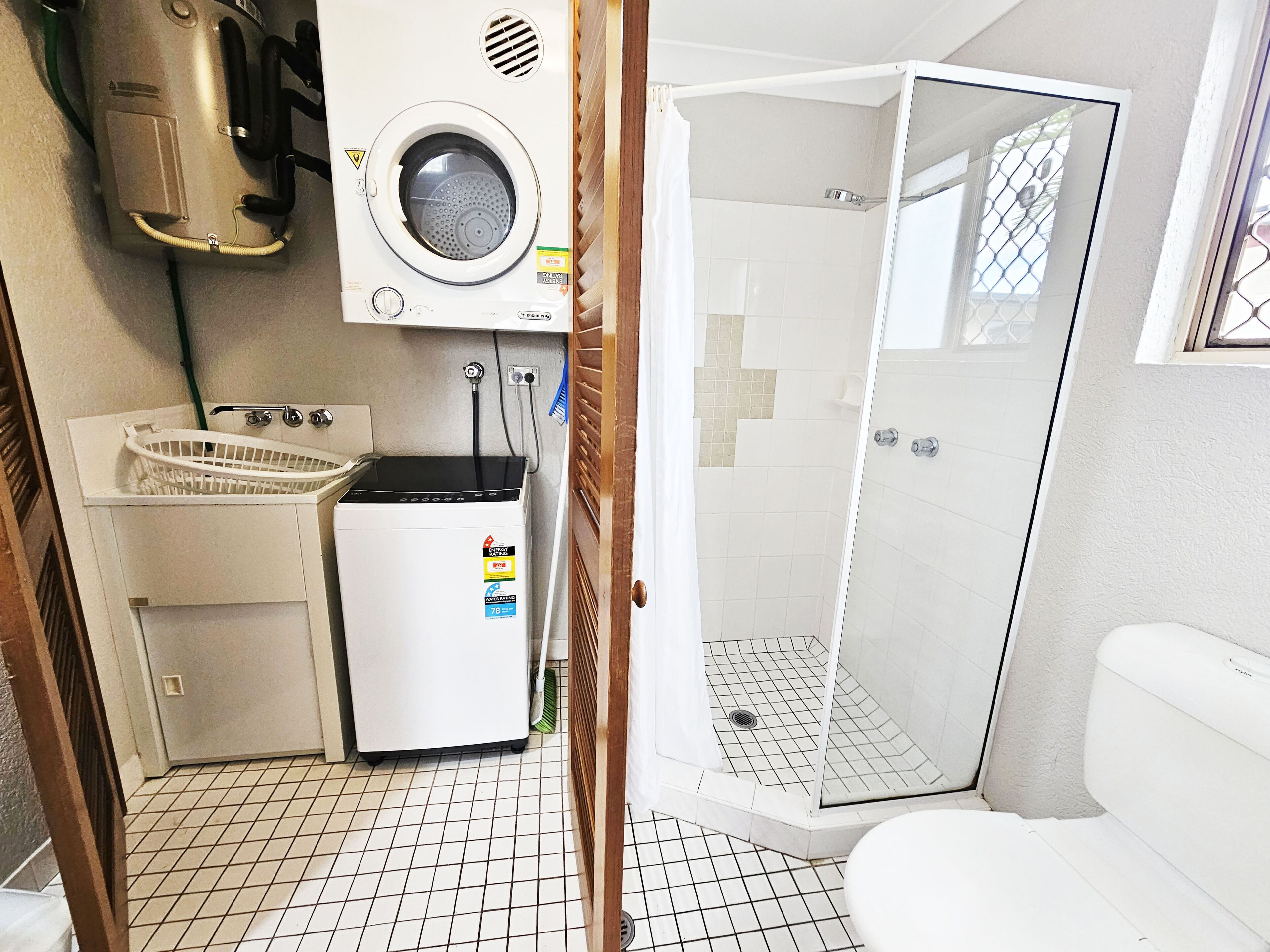 Un baño pequeño con lavadora, lavamanos y cabina de ducha.
