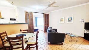 Una sala de estar con comedor, un sofá, un televisor y un ventilador de techo.