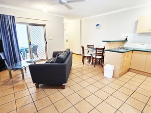 Ein Wohnzimmer mit Sofa, Esstisch, Stühlen und einer Küchenzeile mit Schränken und Spüle.