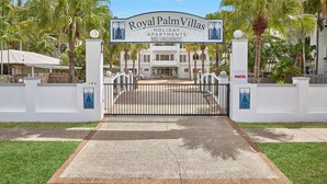 La entrada a Royal Palm Villas, con un camino de entrada porticado, palmeras y un cartel que indica que no hay habitaciones disponibles.