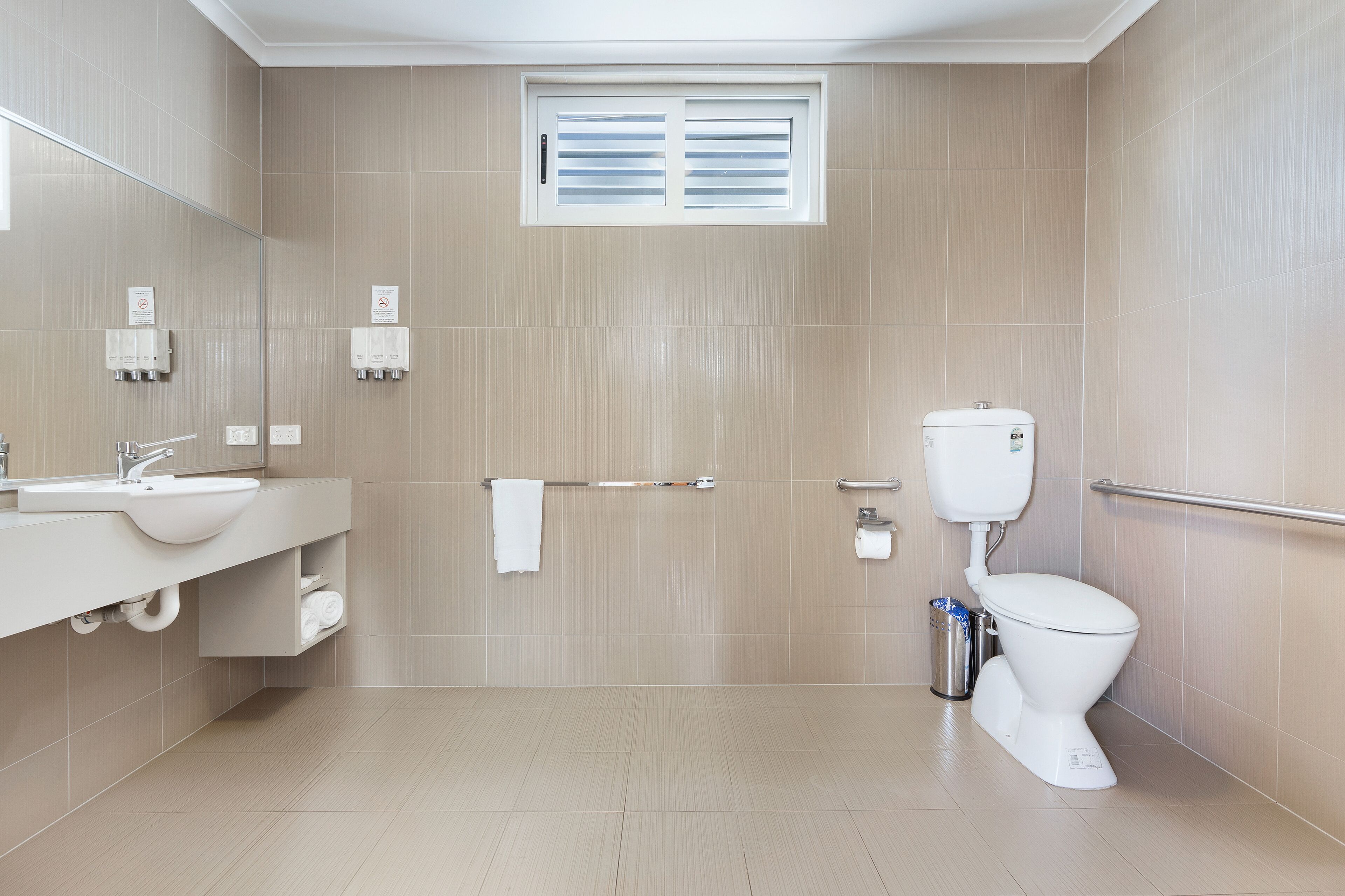 A modern bathroom with a sink, mirror, toilet, and towel rack.