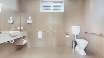 A modern bathroom with a sink, mirror, toilet, and towel rack.