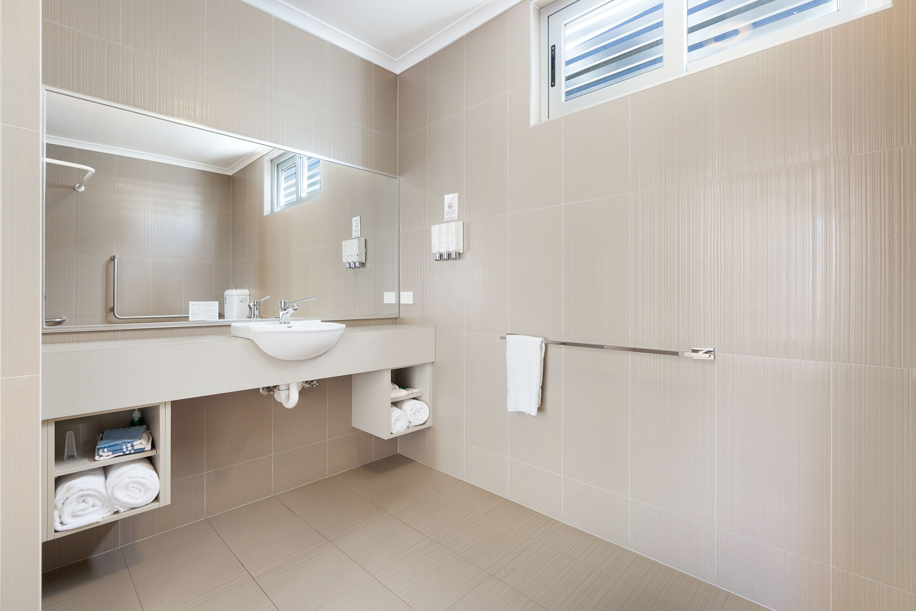 A modern bathroom with a large mirror, a sink, and a towel rack.