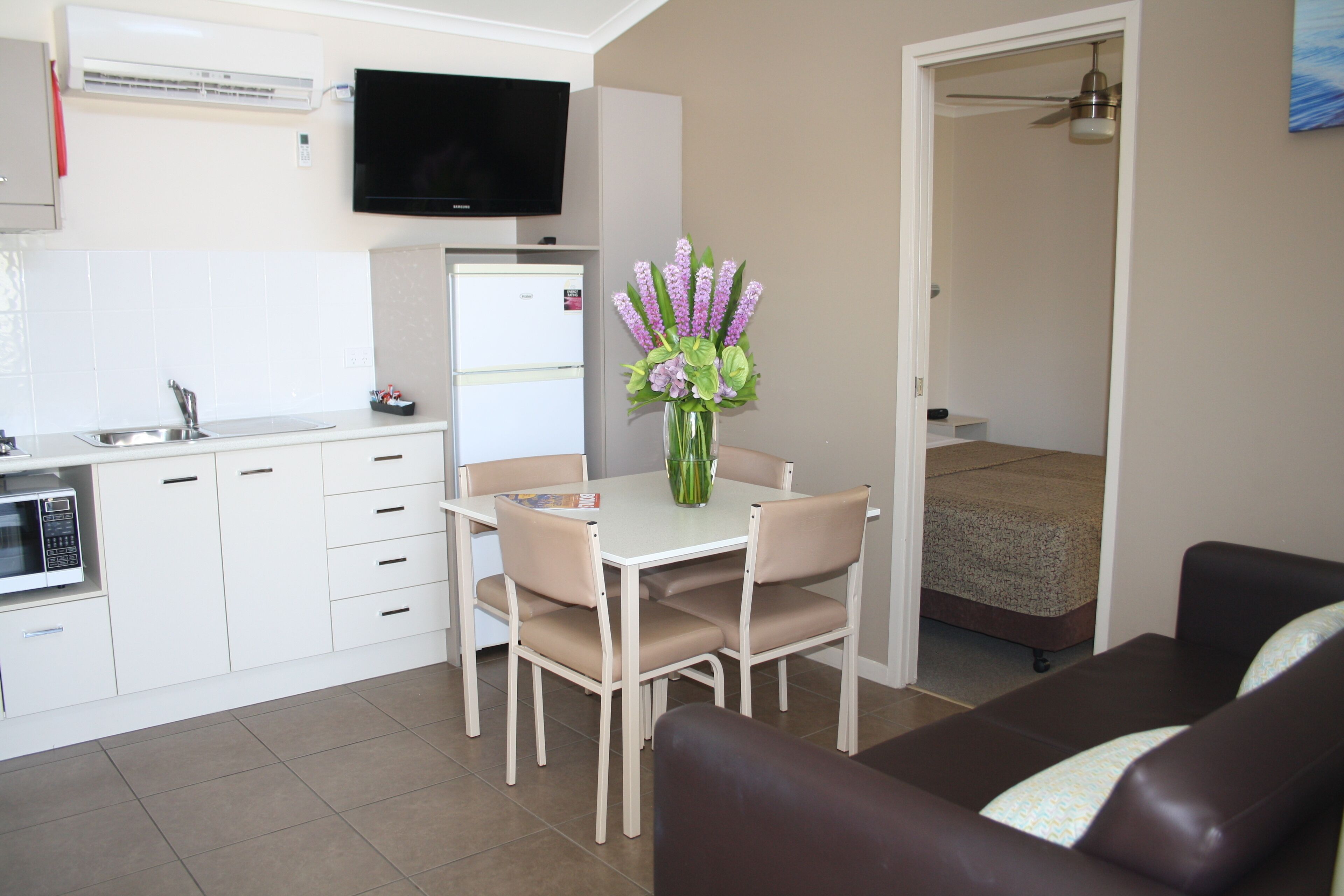 A compact living space with a kitchenette, a dining area, and a small bedroom.