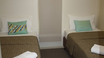 A hotel room with two beds, each with a patterned bedspread and a pillow.