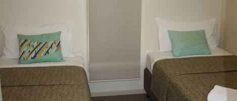 A hotel room with two beds, each with a patterned bedspread and a pillow.