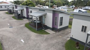 Una hilera de casas móviles modernas con porches adosados, numeradas 16, en un camping bien cuidado.
