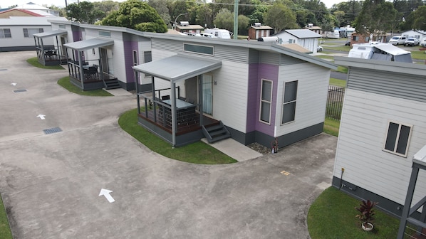 Una hilera de casas móviles modernas con porches adosados, numeradas 16, en un camping bien cuidado.