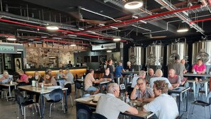 Un restaurante con varias mesas y sillas, una barra y equipo de elaboración de cerveza de estilo industrial al fondo.