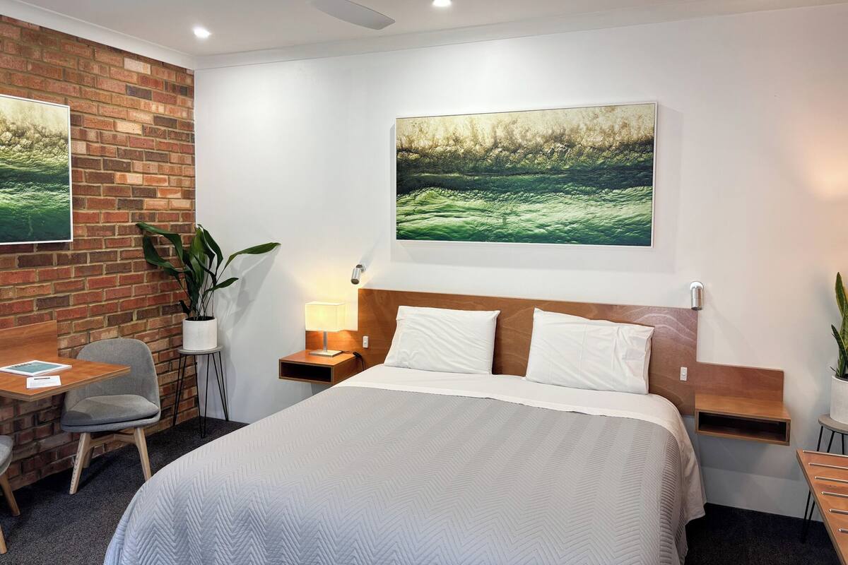 Una habitación de hotel con cama, escritorio, silla y dos mesitas de noche.