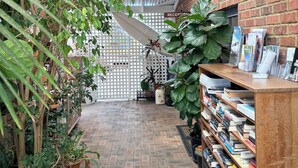 A reception area with a brick wall, a wooden reception desk, and a variety of potted plants. - Edge of the Forest (Margaret River)