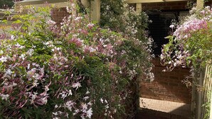 A brick building with a covered entrance and lush flowering plants. - Edge of the Forest (Margaret River)