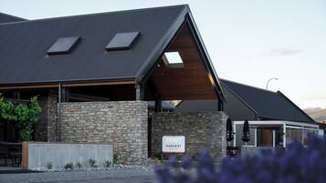 A modern building with a stone facade, a sign reading "HARVEST HOTEL," and a covered outdoor seating area.