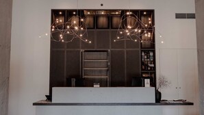 A modern reception area with a large digital display of trees, a reception desk, and a hanging light fixture. - Harvest Hotel (Cromwell)