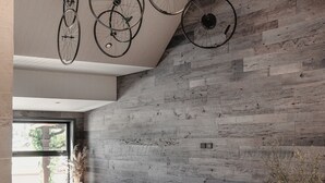A modern interior with a wooden wall, circular seating, and bicycles hanging from the ceiling. - Harvest Hotel (Cromwell)