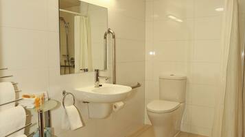 Une salle de bain moderne avec une étagère en verre où sont rangés les articles de toilette, un lavabo, des toilettes et un espace douche.