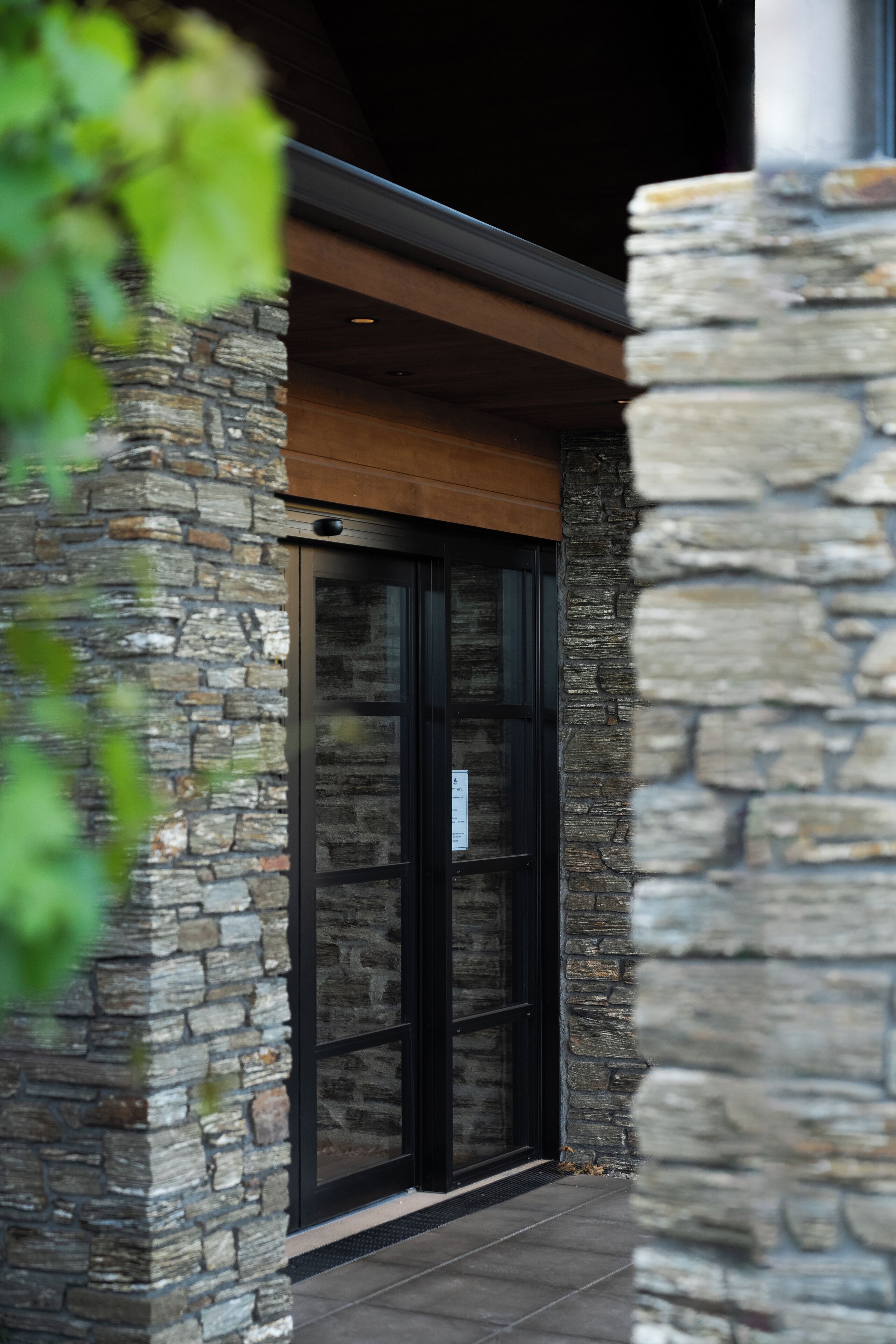 A stone building with a glass door and a wooden beam above it.