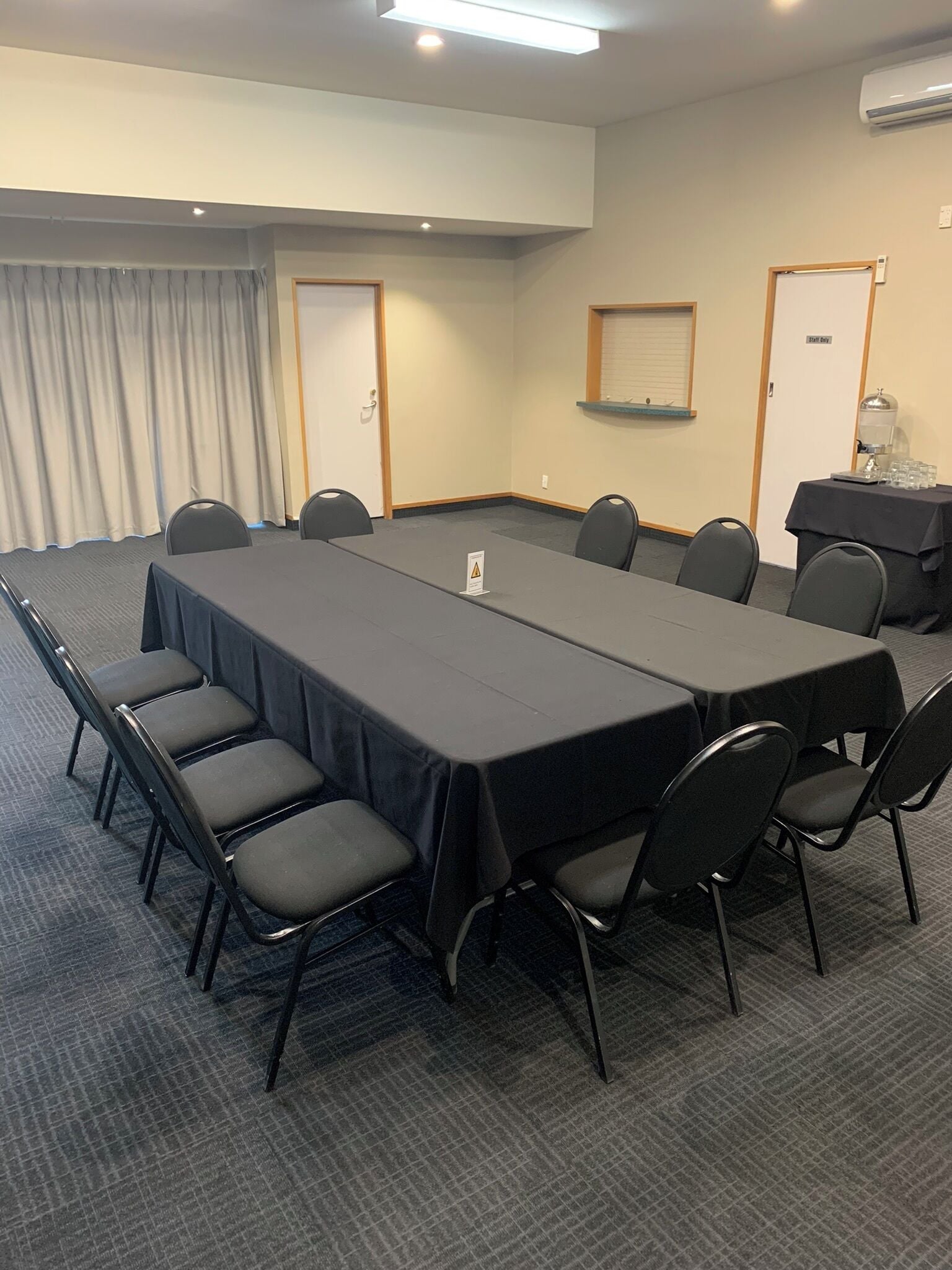 Un salón de conferencias con una larga mesa, sillas, una estación de café y una puerta con la indicación 'Sólo personal'.